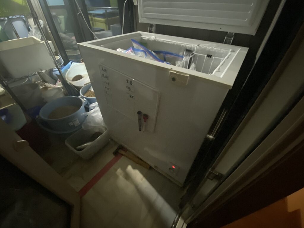 長年使用している上開き冷凍庫。庫内には霜が厚くつき、ブルーベリーや肉類などがジップロックでぎっしり収納されている。収納スペースが限界に達している様子。