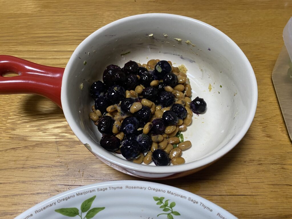 白い器に盛られた納豆とブルーベリーの組み合わせ。発酵食品と抗酸化作用のある果物を合わせたユニークな健康食。