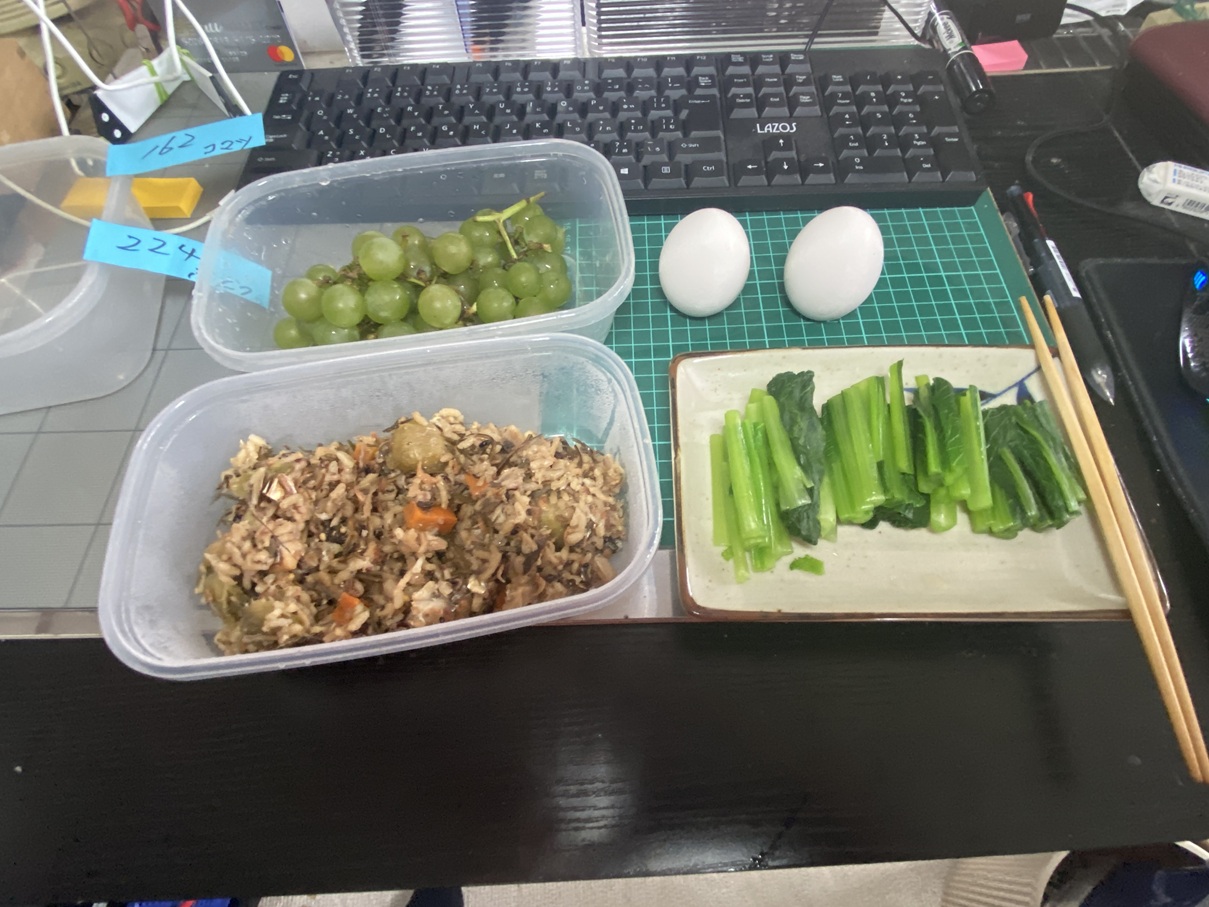 小松菜のおひたし、納豆ご飯、ゆで卵、ディラウェアぶどうを並べた夕食セット。容器に小分けされ、バランスの良い家庭の食卓の様子。