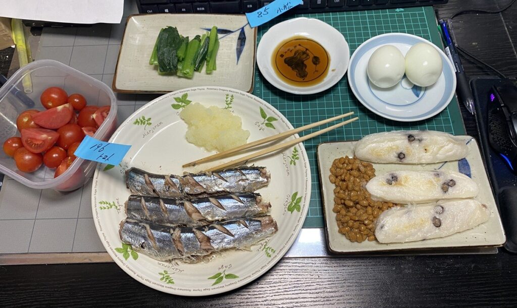 サンマの塩焼きに大根おろし、納豆、ゆで卵、切り餅、小松菜のおひたし、ミニトマトを添えた和定食の食卓。栄養バランスの整った家庭の健康食メニュー。