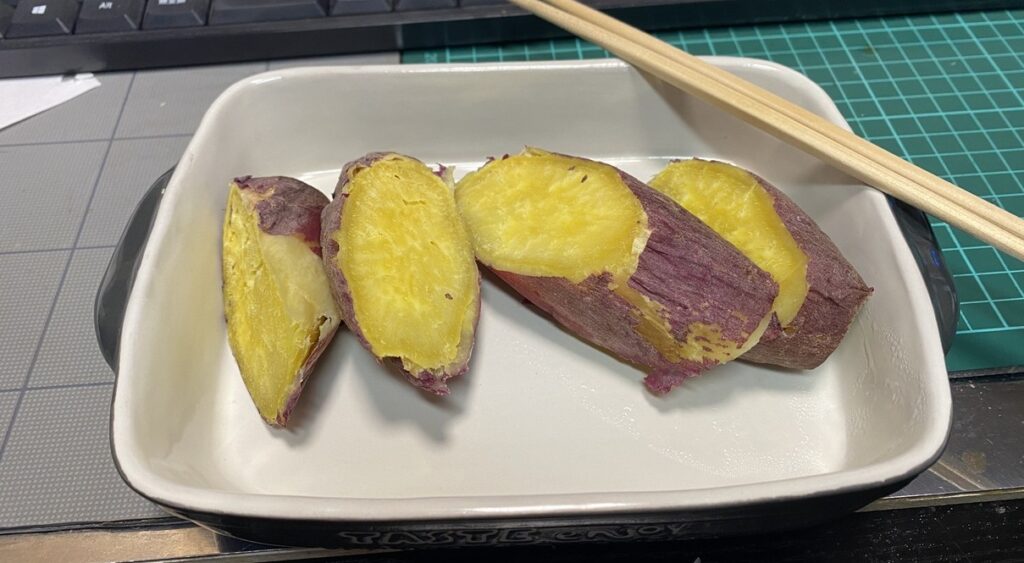 電子レンジで温めたしっとり甘い焼き芋。夜食にぴったりの優しい味わいで、皮ごと食べられるヘルシーな一皿。白い器に盛られて湯気がほのかに立つ。