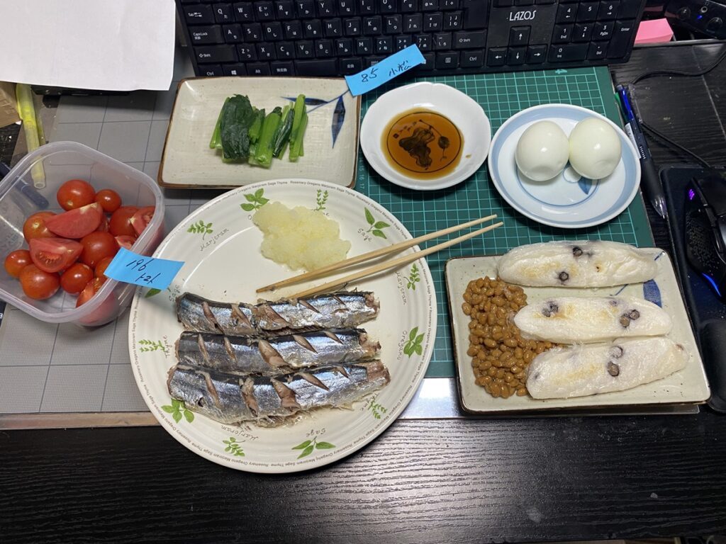 サンマの塩焼きに大根おろし、納豆、ゆで卵、切り餅、小松菜のおひたし、ミニトマトを添えた和定食の食卓。栄養バランスの整った家庭の健康食メニュー。