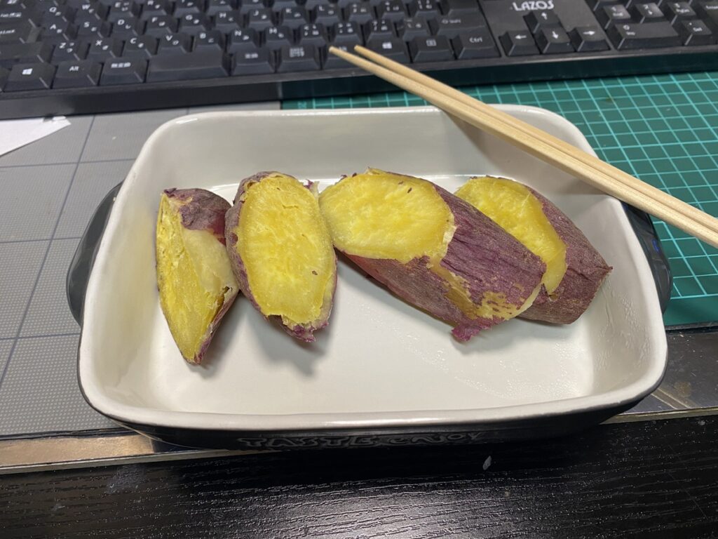 電子レンジで温めたしっとり甘い焼き芋。夜食にぴったりの優しい味わいで、皮ごと食べられるヘルシーな一皿。白い器に盛られて湯気がほのかに立つ。