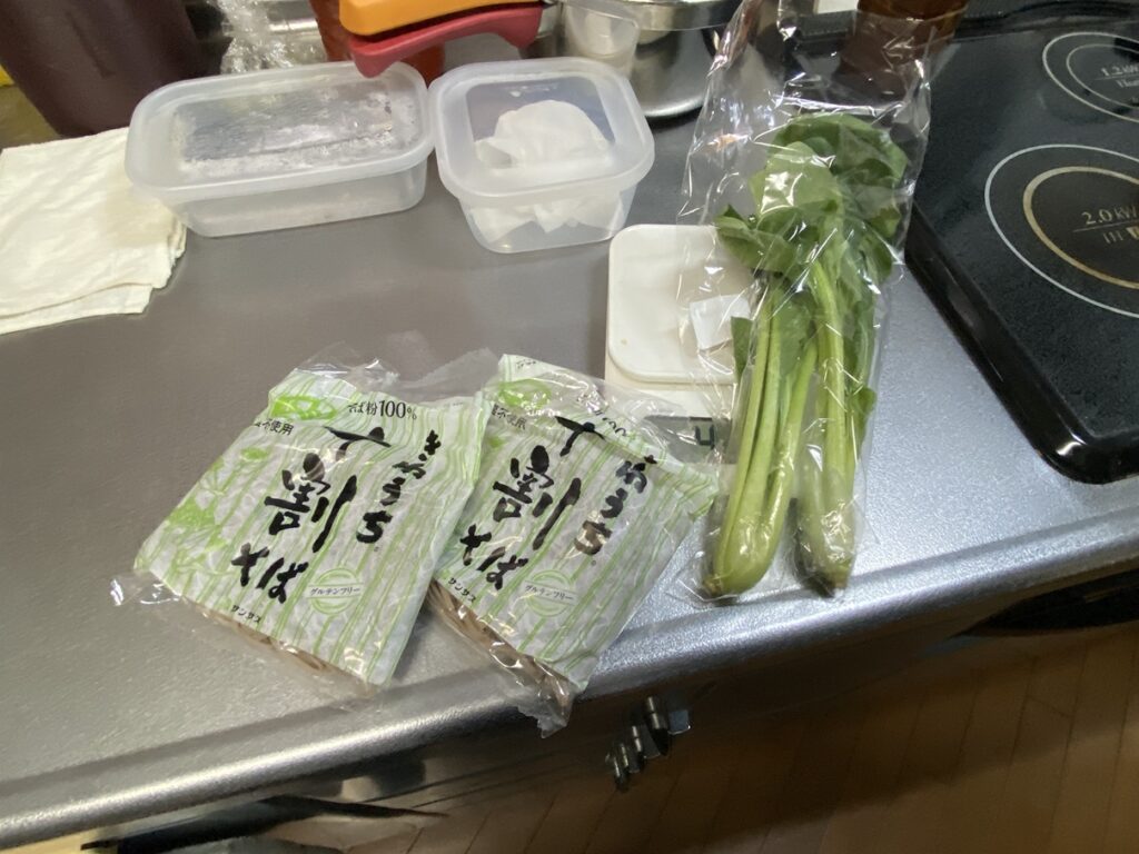 十割そば2袋と小松菜を調理前に並べた様子。夜の夕食づくりの準備。
